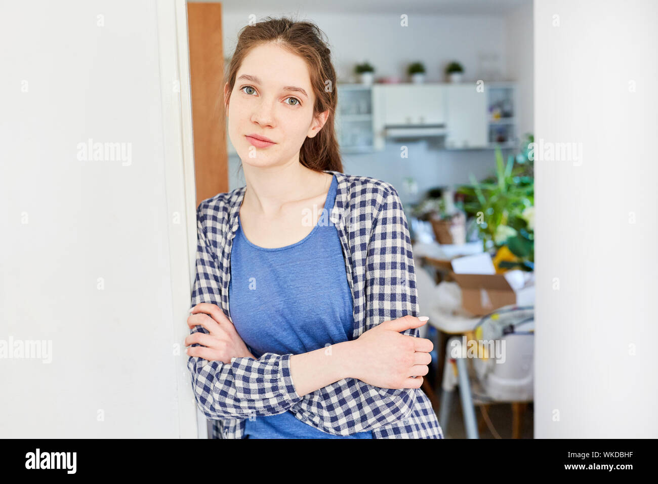 Giovane donna come un inquilino muovendosi nel suo appartamento con bracci ripiegati Foto Stock