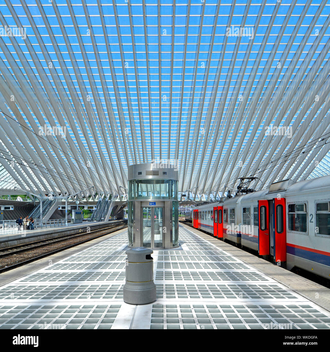 Quasi deserta stazione ferroviaria piattaforma su Domenica a Liegi in Belgio al di sotto di moderna costruzione tetto di vetro soffitto blu cielo estate giorno carrelli su una traccia Foto Stock