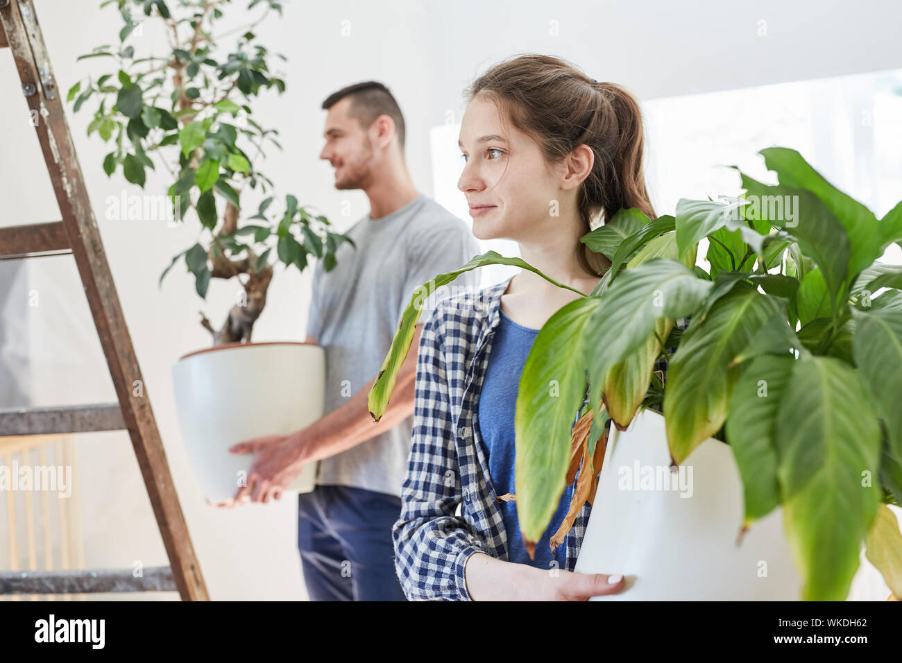 Coppia giovane porta piante verdi nel comune appartamento o casa nuova Foto Stock