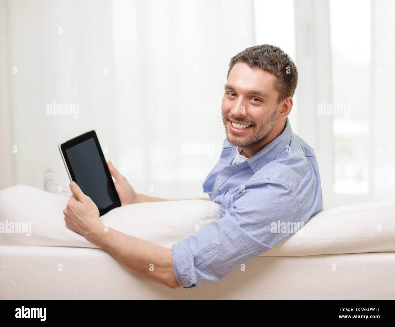 Uomo sorridente lavora con tablet pc a casa Foto Stock