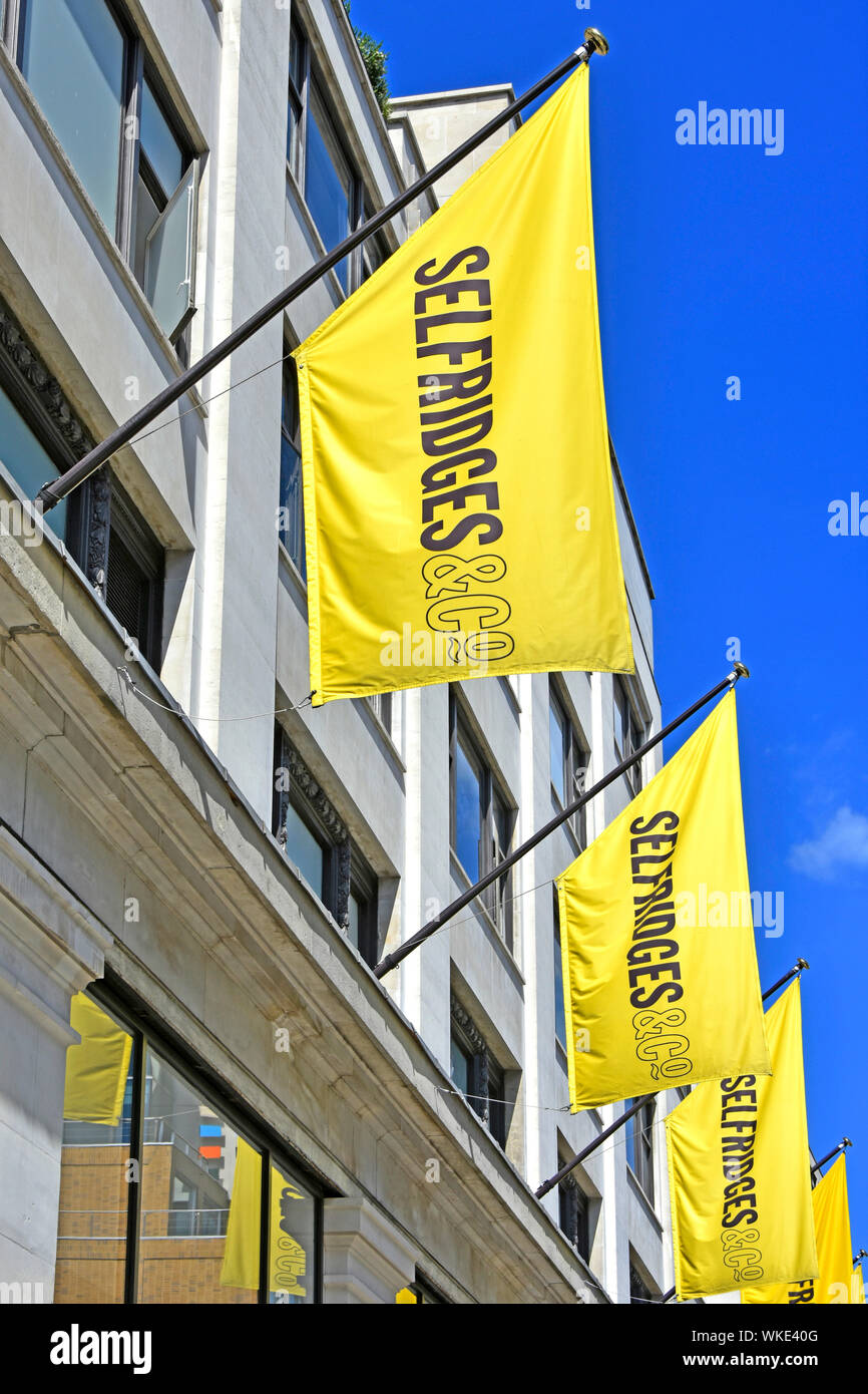 Dal grande magazzino Selfridges retail business banner giallo sopra negozio pubblicizza l'immagine di marca e ripetere sulle bandiere identici per impatto London West End Regno Unito Foto Stock