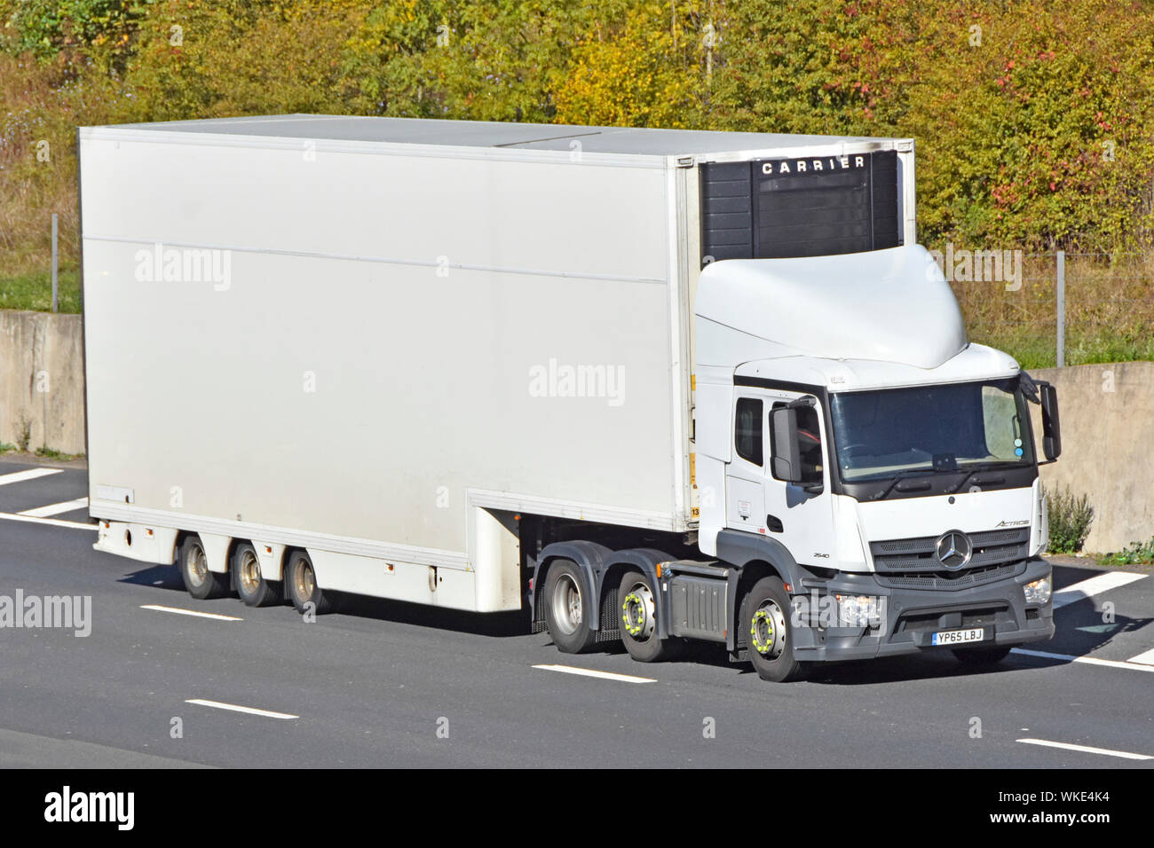 Lato anteriore e di bianco pulito non marcati consegna articolato rimorchio con scambiatore di calore Carrier & white hgv Mercedes camion unità carrello guida lungo l'autostrada UK Foto Stock