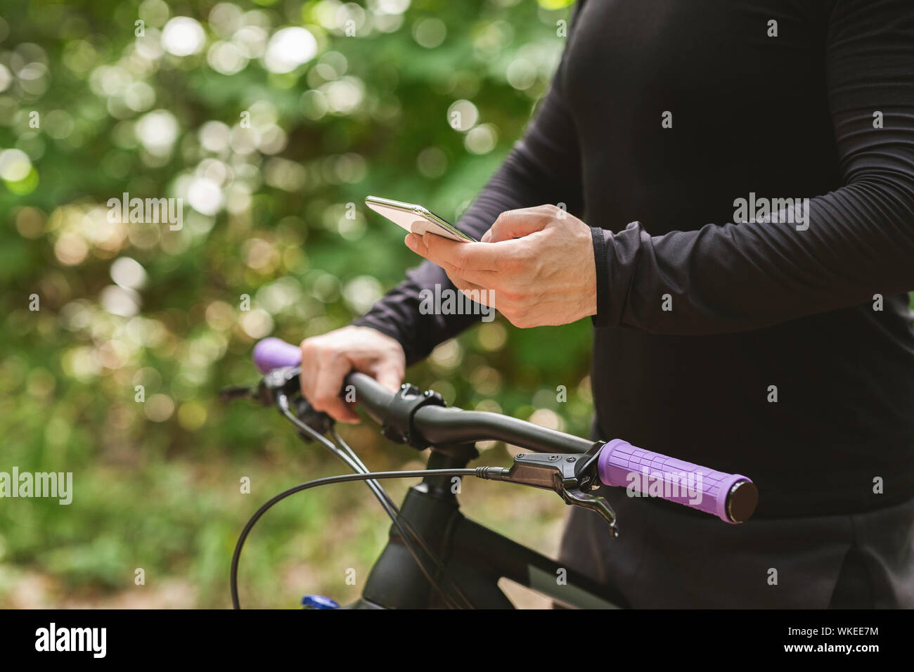 Chiusura del ciclista holding bike e utilizzando il telefono Foto Stock