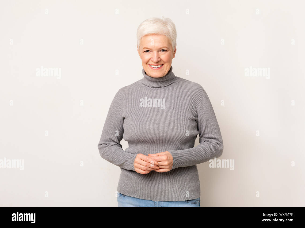 Timido senior lady in posa in telecamera sulla luce di sfondo per studio Foto Stock