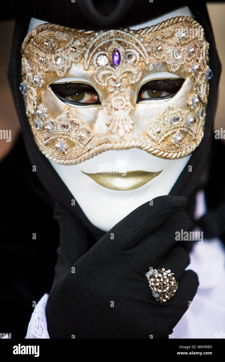 Uomo veneziano in costume nero con una maschera dorata Foto stock - Alamy