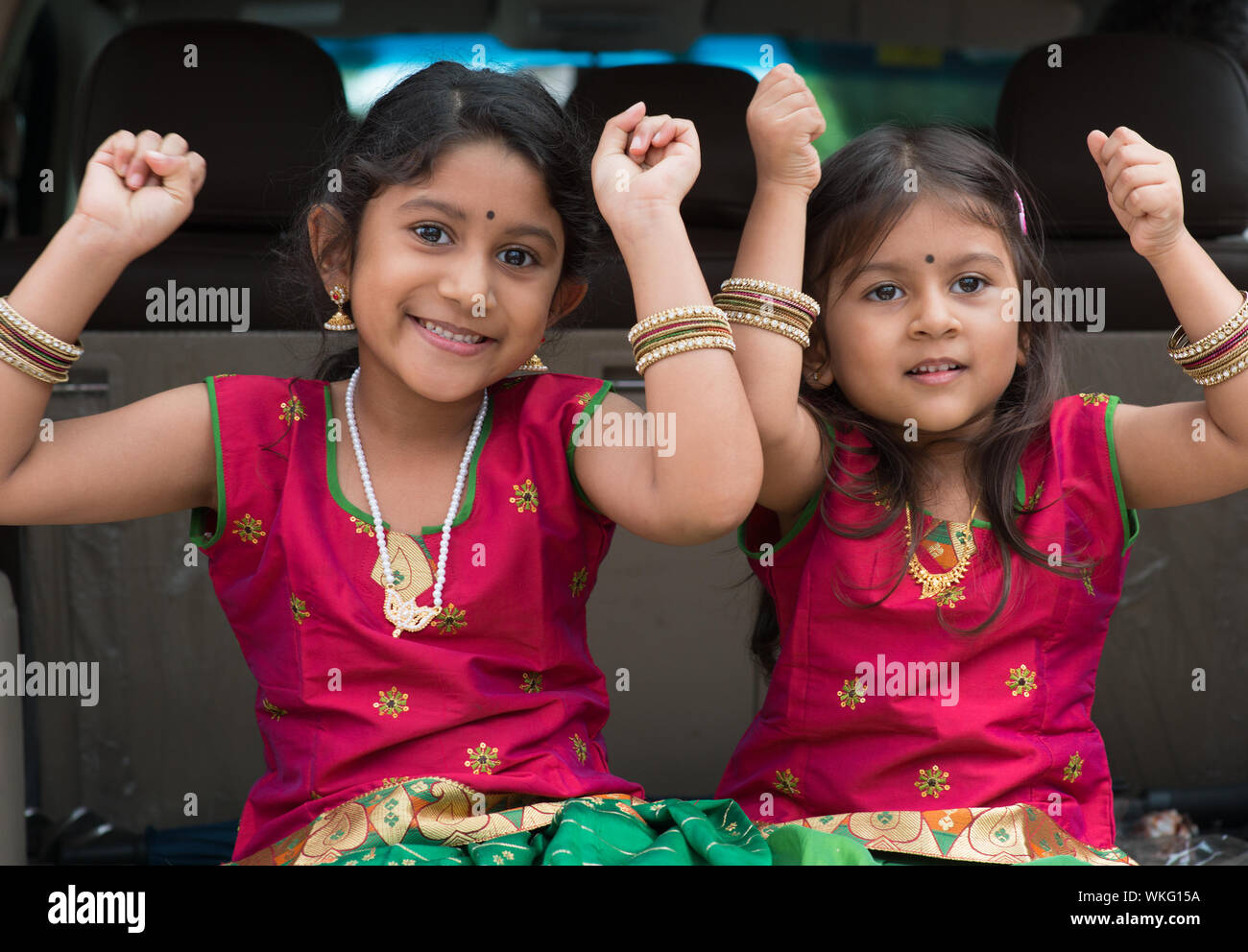 Felice ragazze indiano seduti in auto, sorridenti pronti per andare in vacanza. Bambini asiatici. Foto Stock