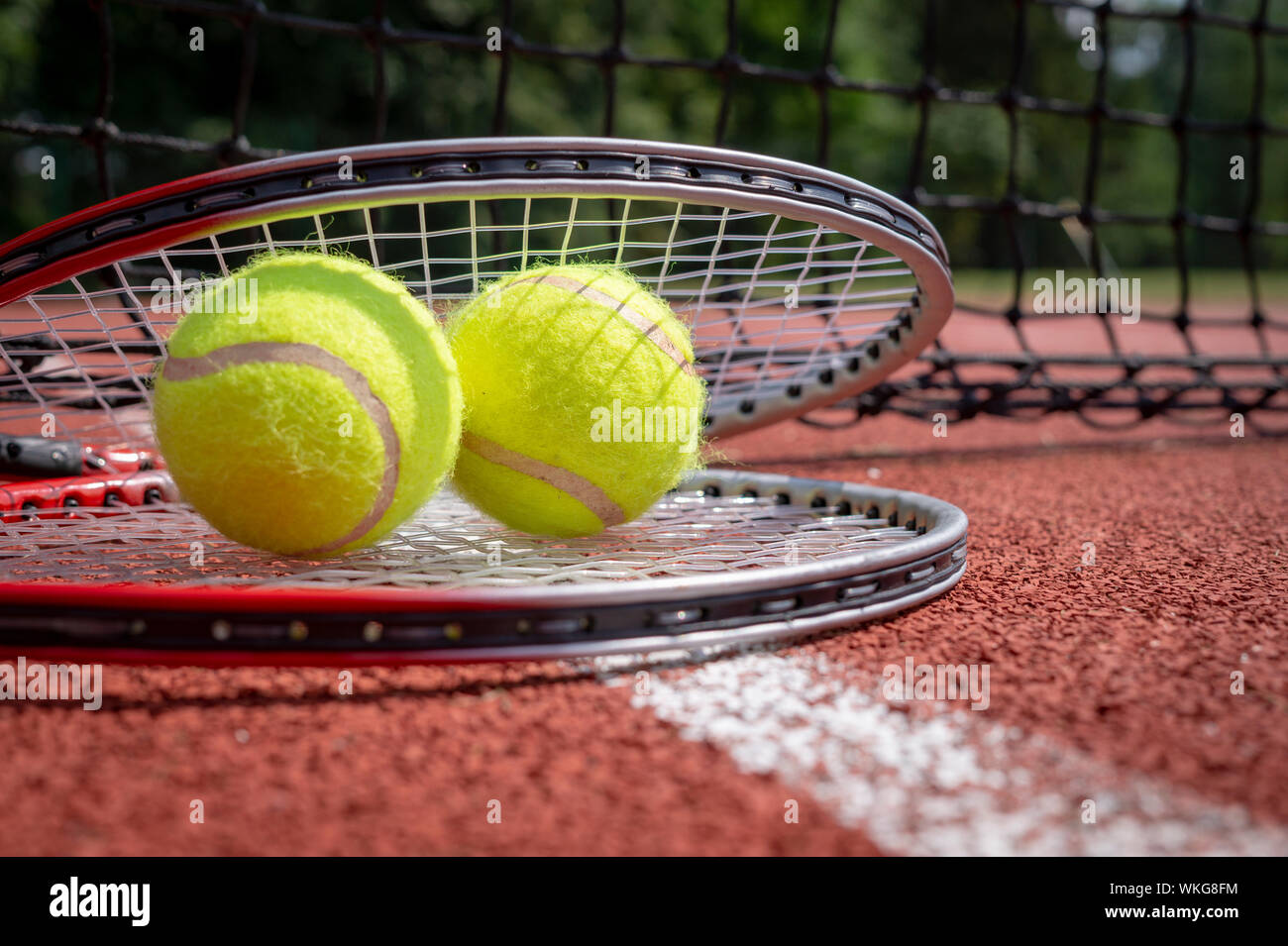Due palle da tennis in appoggio sulla sommità di una racchetta da tennis su  un disco rosso corte, basso angolo di visione e la messa a fuoco selettiva  Foto stock - Alamy