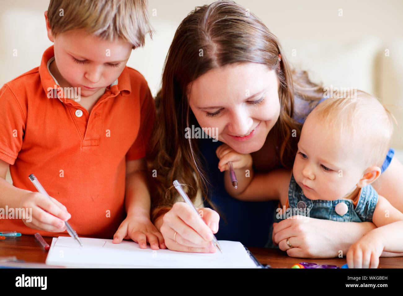 Giovane madre e i suoi due bambini disegno insieme. Può essere utilizzato anche nella scuola dell'infanzia/contesto diurni Foto Stock