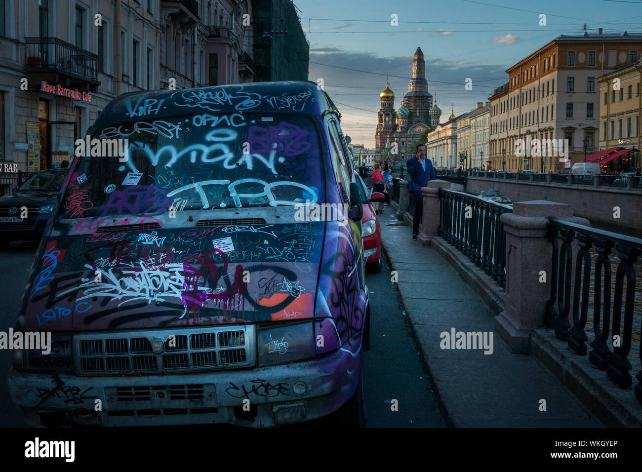 Immagine giustapposti di auto coperto di graffiti sul canale Griboyedova embankment street con la chiesa del sangue versato in background, San Pietroburgo, Foto Stock