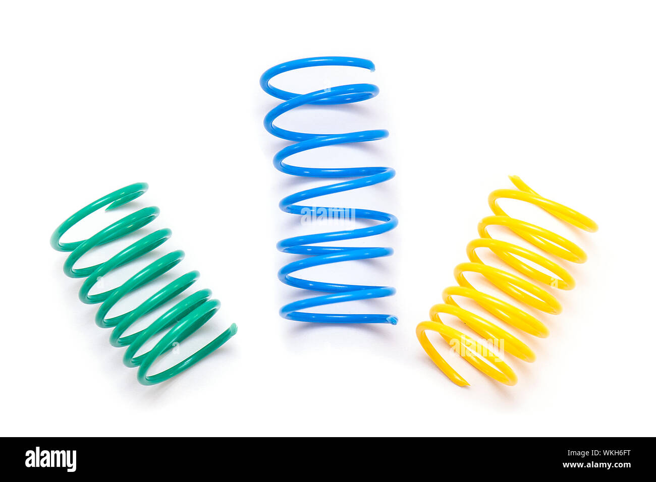 Il giallo, il verde e il blu in plastica giocattolo a molla o spirali isolati su sfondo bianco Foto Stock