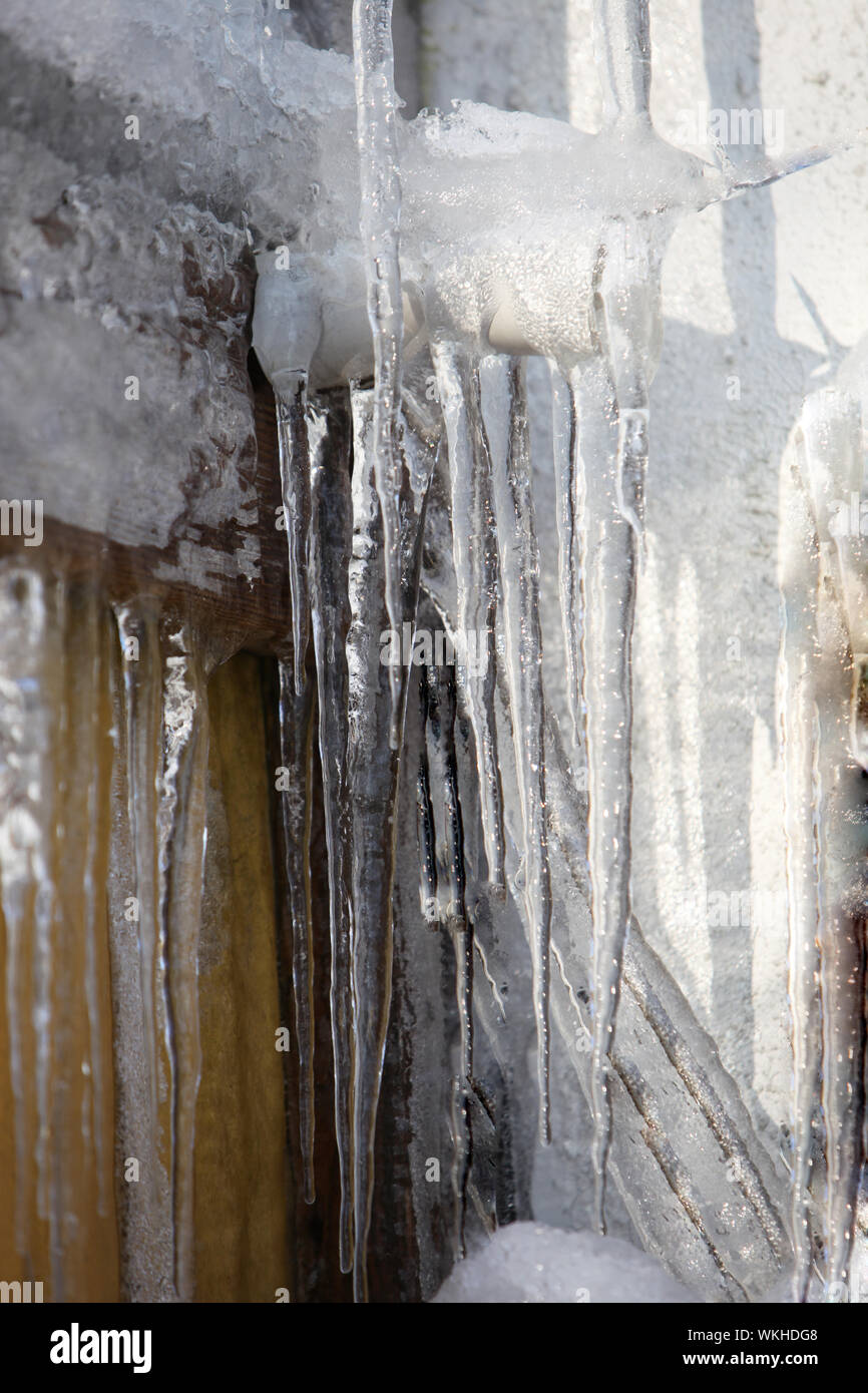 Grandi ghiaccioli sul muro di casa, gronda del tetto e il tubo verso il basso-close-up Foto Stock