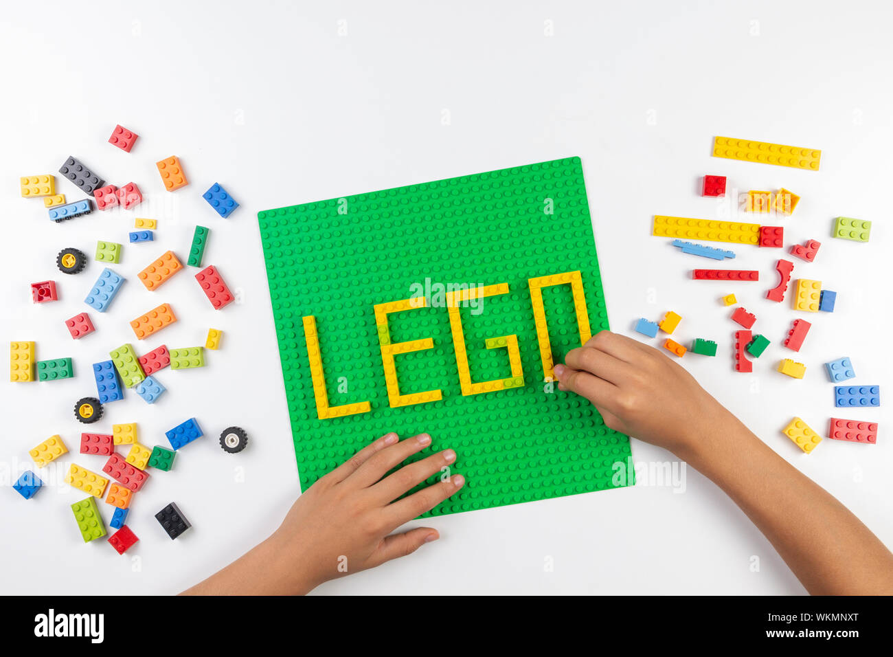 Vilnius, Lituania - 17 August, 2019: bambino mani fare parola LEGO sulla piastra di base verde da coloratissimi blocchi Lego sul tavolo bianco Foto Stock