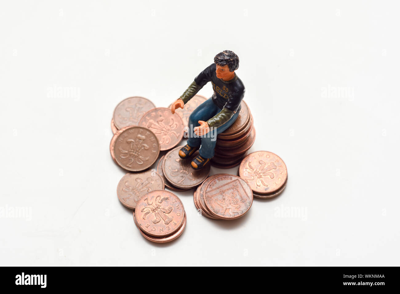 Rendendo il risparmio di denaro e di rendere il concetto di denaro. L'uomo si siede su una pila su monete Foto Stock