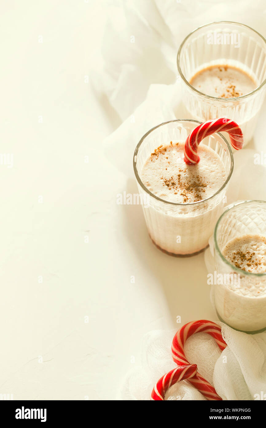 Tradizionale winter in casa gustosi cocktail di Natale zabaione con latte, il rum e la cannella e la noce moscata decorate candy cane su sfondo bianco Foto Stock