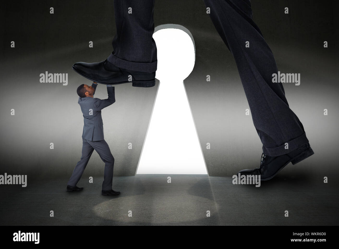 Immagine composita di imprenditore il rafforzamento sul piccolo imprenditore contro la camera grigia con foro di serratura porta Foto Stock