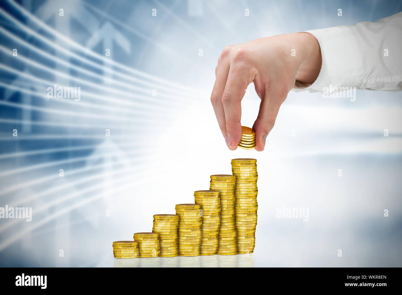 Imprenditore tenendo delle monete in euro contro la freccia di grafica in blu e bianco Foto Stock