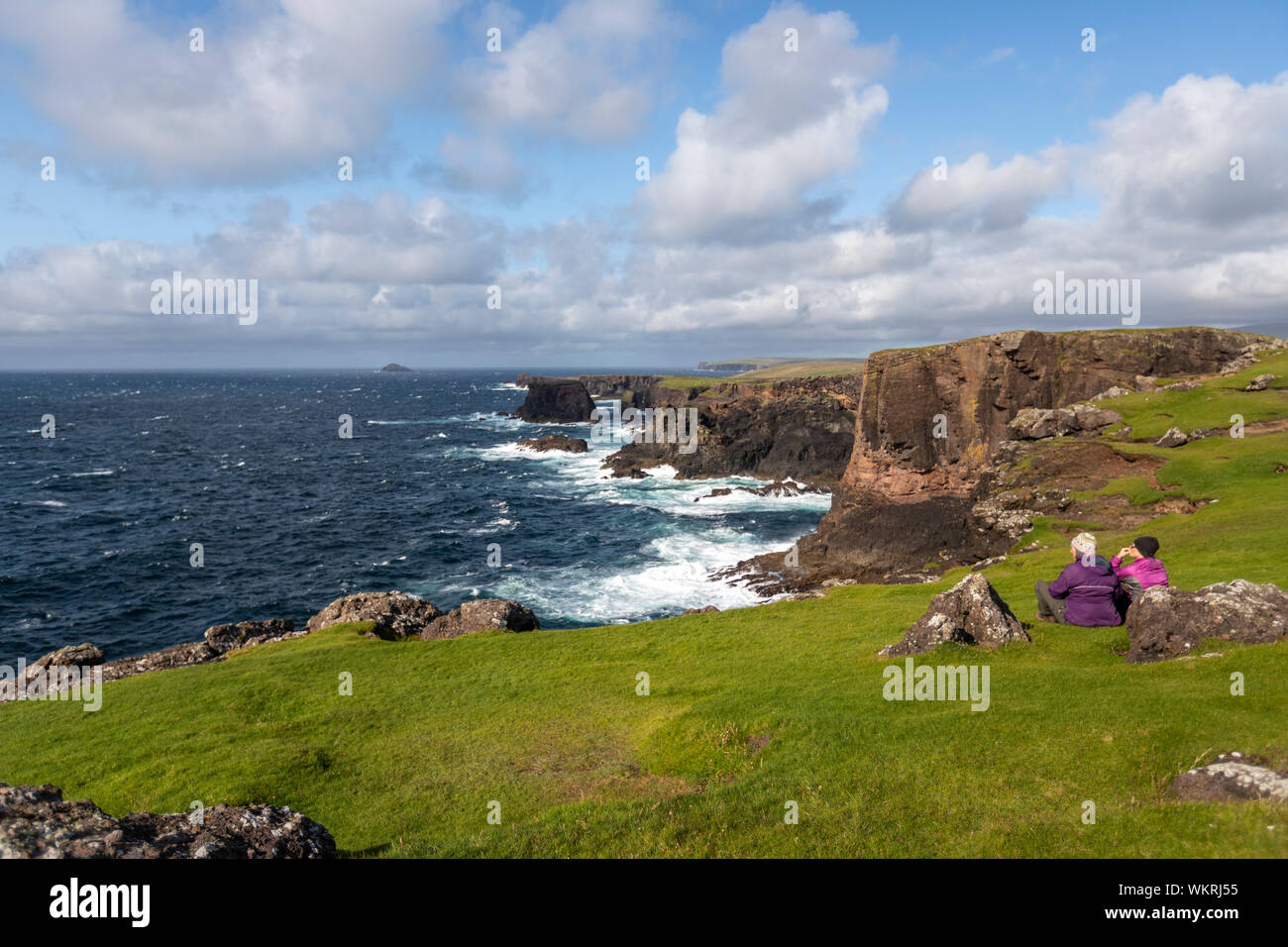 Coppia di donne che cercano le scogliere paesaggio nella penisola Northmavine, Continentale, Shetland, Scotland, Regno Unito Foto Stock