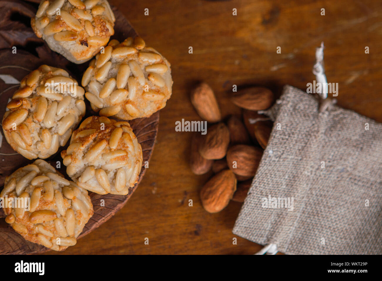 Primo piano con piastra panellets catalana e alcune mandorle tostate in una piccola borsa su di un tavolo di legno. Deserto tipici in Catalogna per la Castanyada Foto Stock