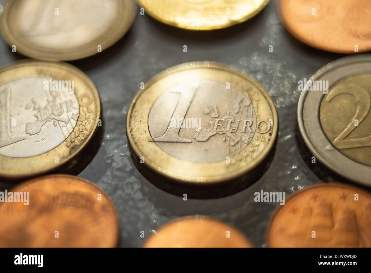 Shiny 1 monete in euro e di alcuni altri intorno, close up su un tavolo di vetro. Foto Stock