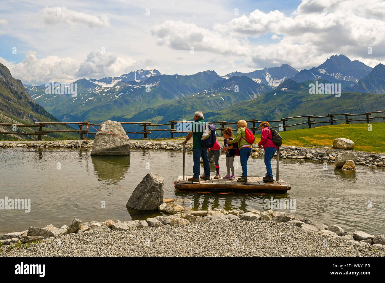 Una famiglia multigenerazionale divertirsi attraversando uno stagno su una zattera al Pavillon stazione ferroviaria della Skyway Monte Bianco, Courmayeur, Aosta, Italia Foto Stock