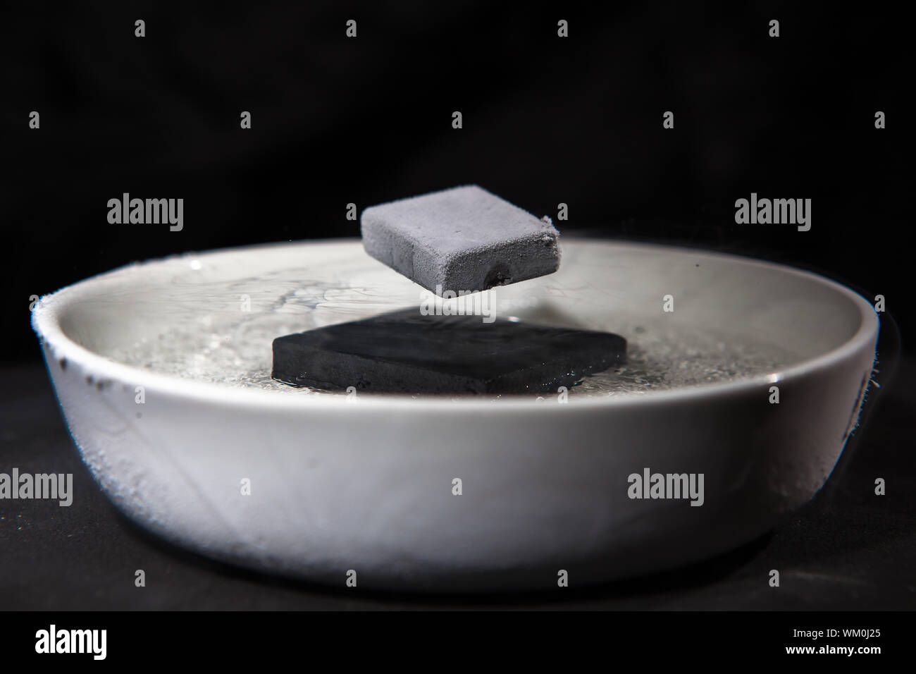 La fisica in azione - esperimento con materiali supraconductive, quando raffreddato in azoto liquido, questi magneti sono abbastanza forti per rendere ogni altro Foto Stock