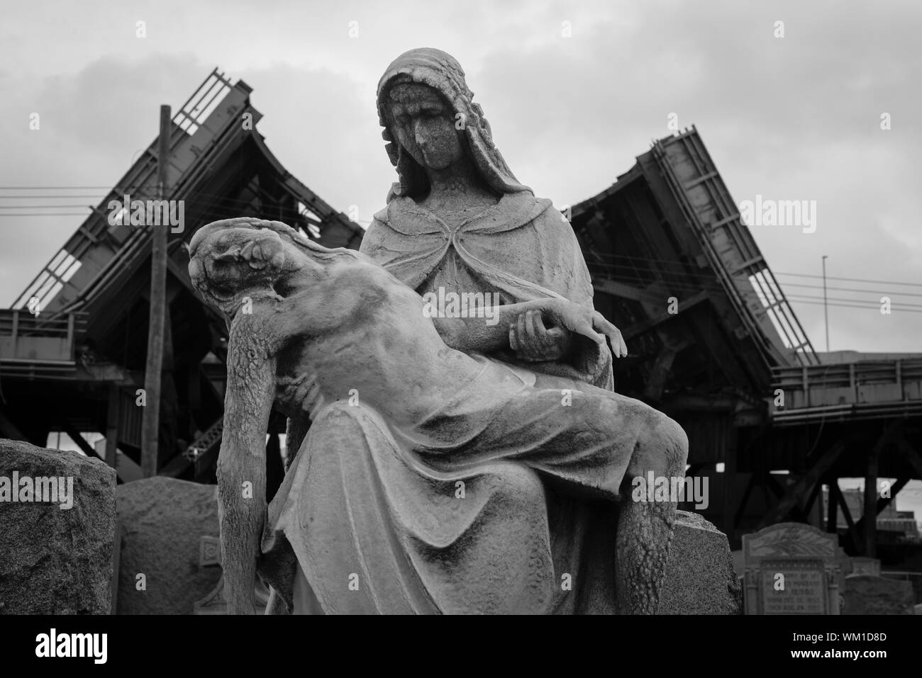 Una lapide raffigurante Maria con Gesù di fronte alla parziale demolizione del ponte di Kosciuszko nel Calvary Cemetery in Maspeth, Queens, a New York. Foto Stock