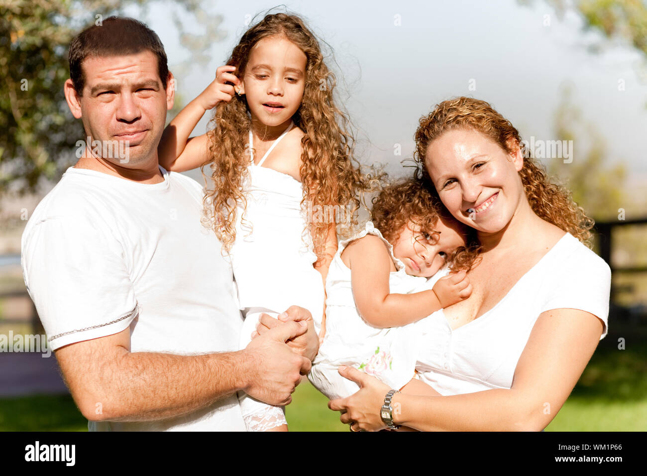 I genitori caucasici che trasportano i loro bambini nel parco Foto Stock