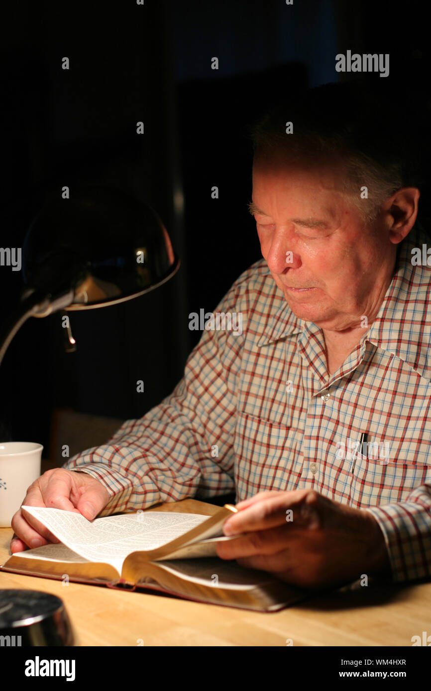 Uomo anziano leggendo la Bibbia da lampligh Foto Stock
