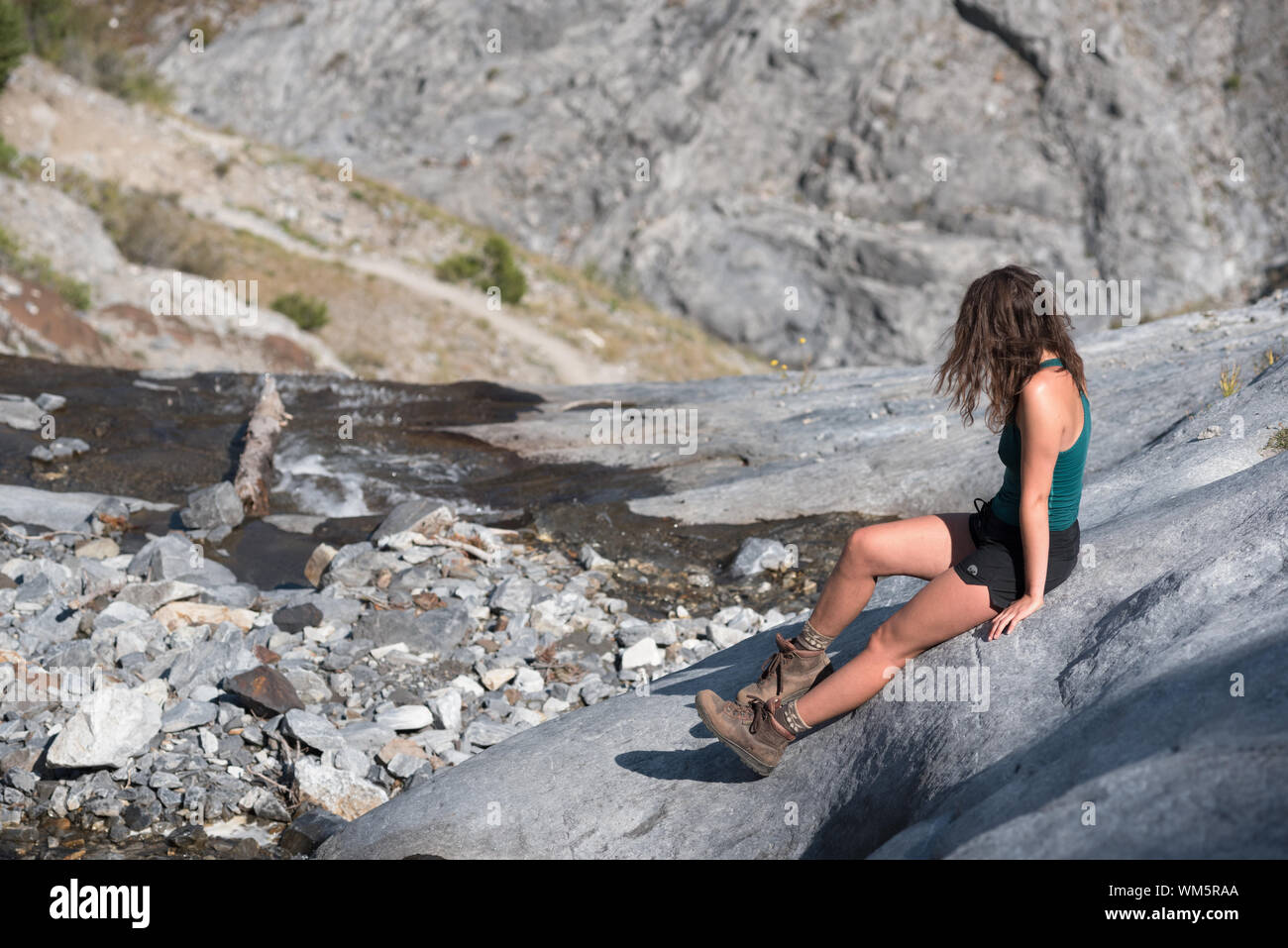 Donna seduta su un pendio di roccia, Wallowa Mountains, Oregon. Foto Stock