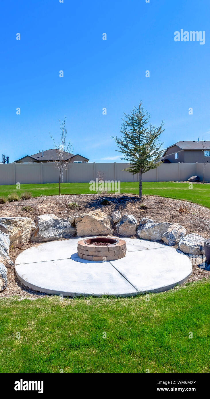 Circolare di una buca per il fuoco circondata da rocce nel mezzo del cortile erboso di un home Foto Stock