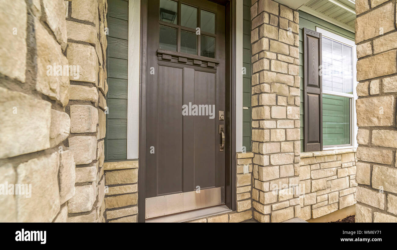 Telaio Panorama Home ingresso con una vetrata in vetro marrone porta in legno e pietra e parete di mattoni Foto Stock