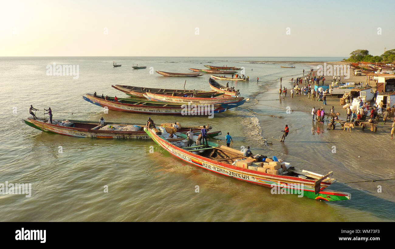 Persone con imbarcazioni al fiume Gambia contro il cielo chiaro Foto Stock