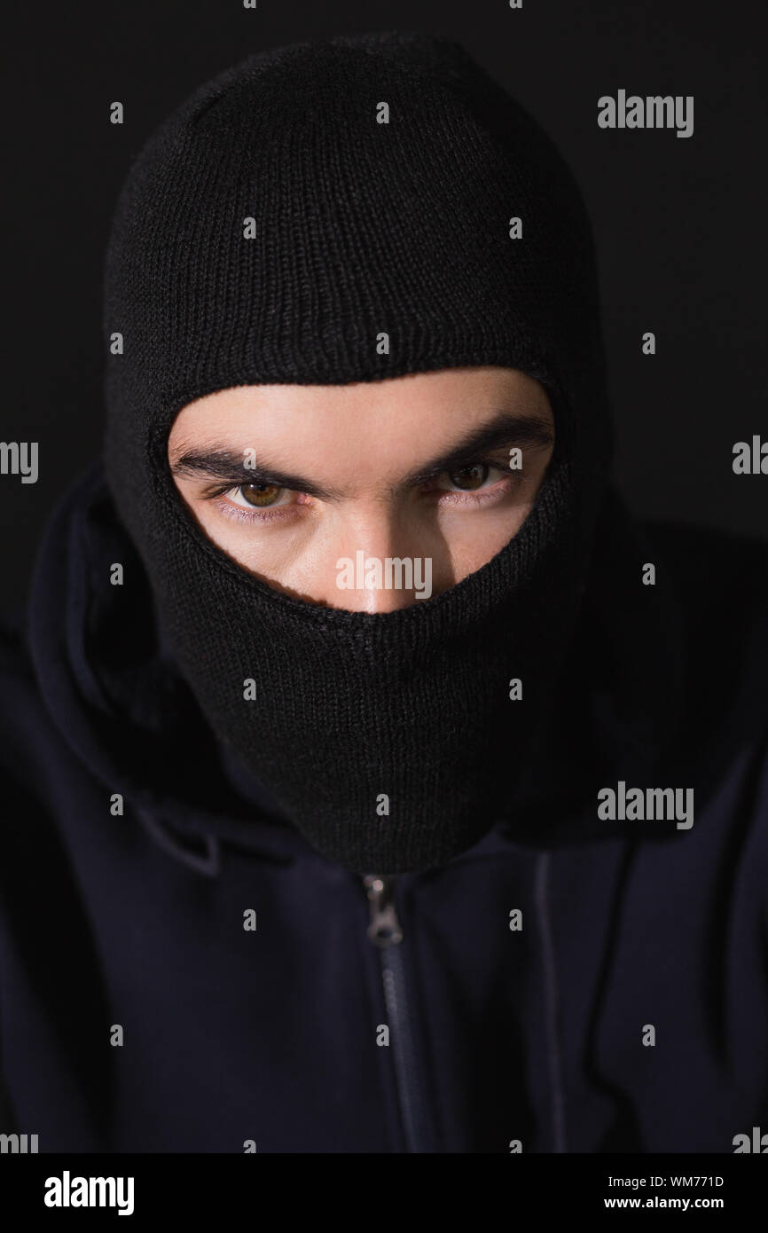 Ritratto del ladro che indossa un passamontagna su sfondo nero Foto stock -  Alamy