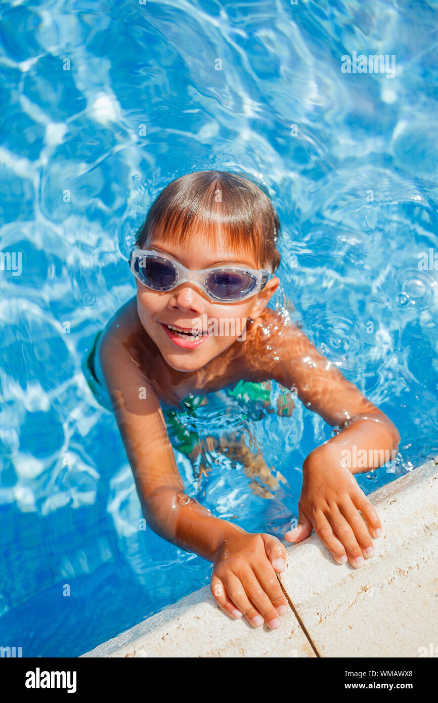 Carino piccolo felice ragazzo in occhiali nuoto e snorking in piscina Foto Stock