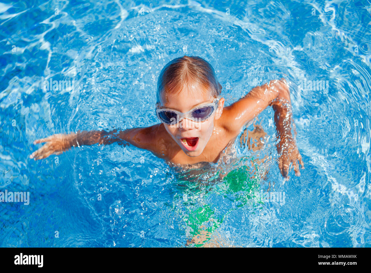 Carino piccolo felice ragazzo in occhiali nuoto e snorking in piscina Foto Stock