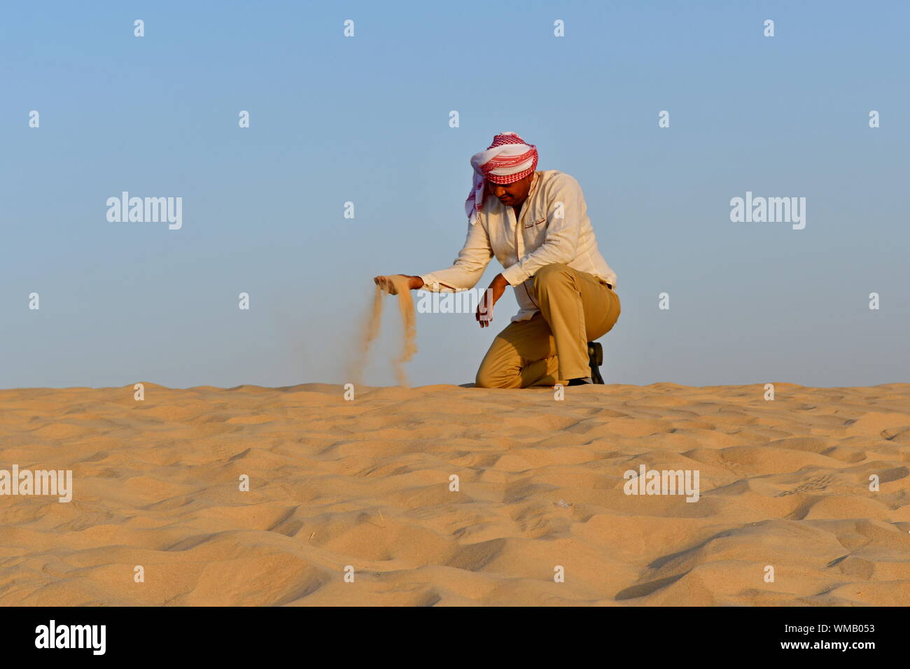 L'uomo spargimento sabbia in spiaggia contro il cielo chiaro Foto Stock