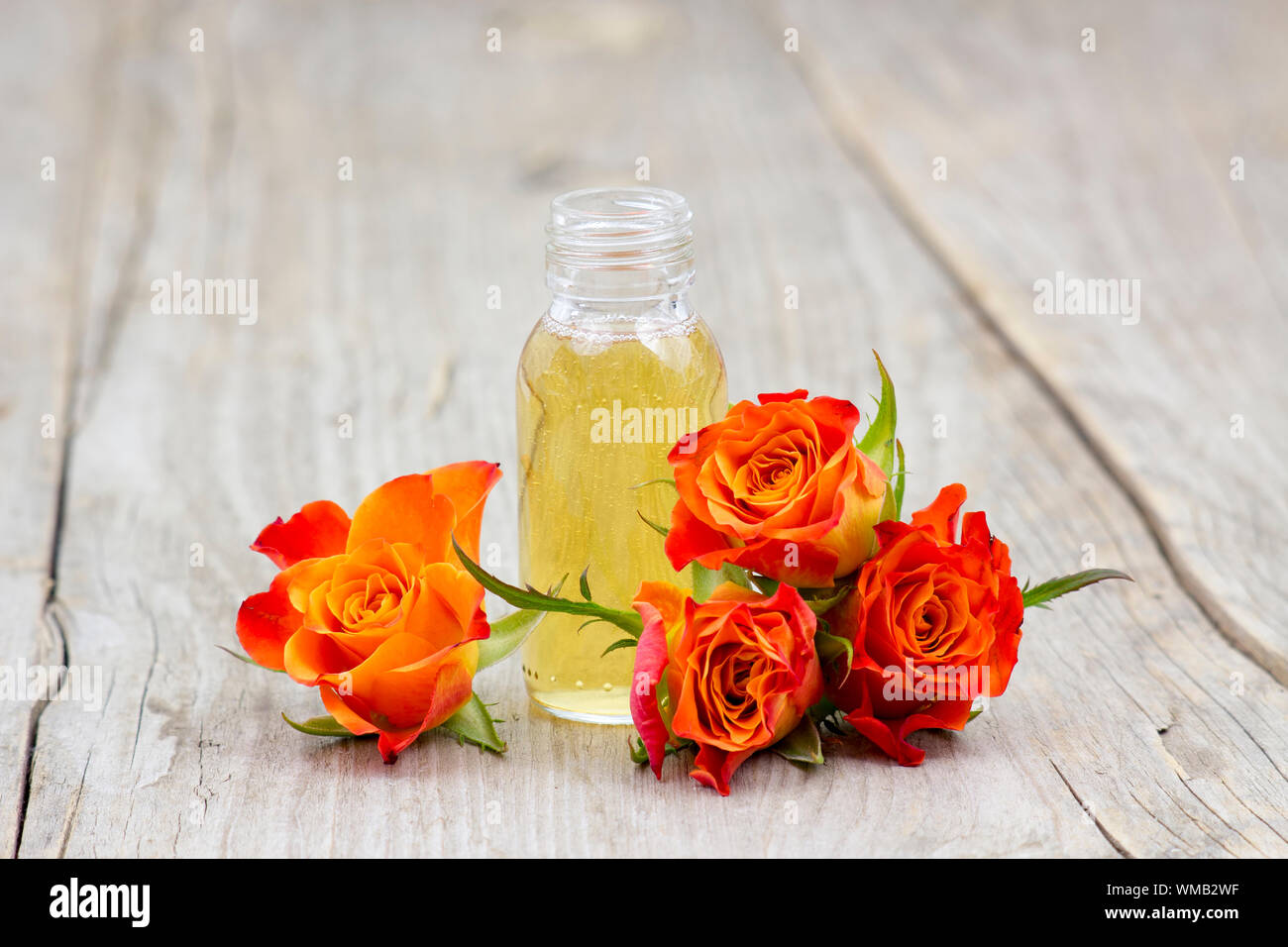 Olio da Bagno e orange rose sul vecchio sfondo di legno Foto Stock