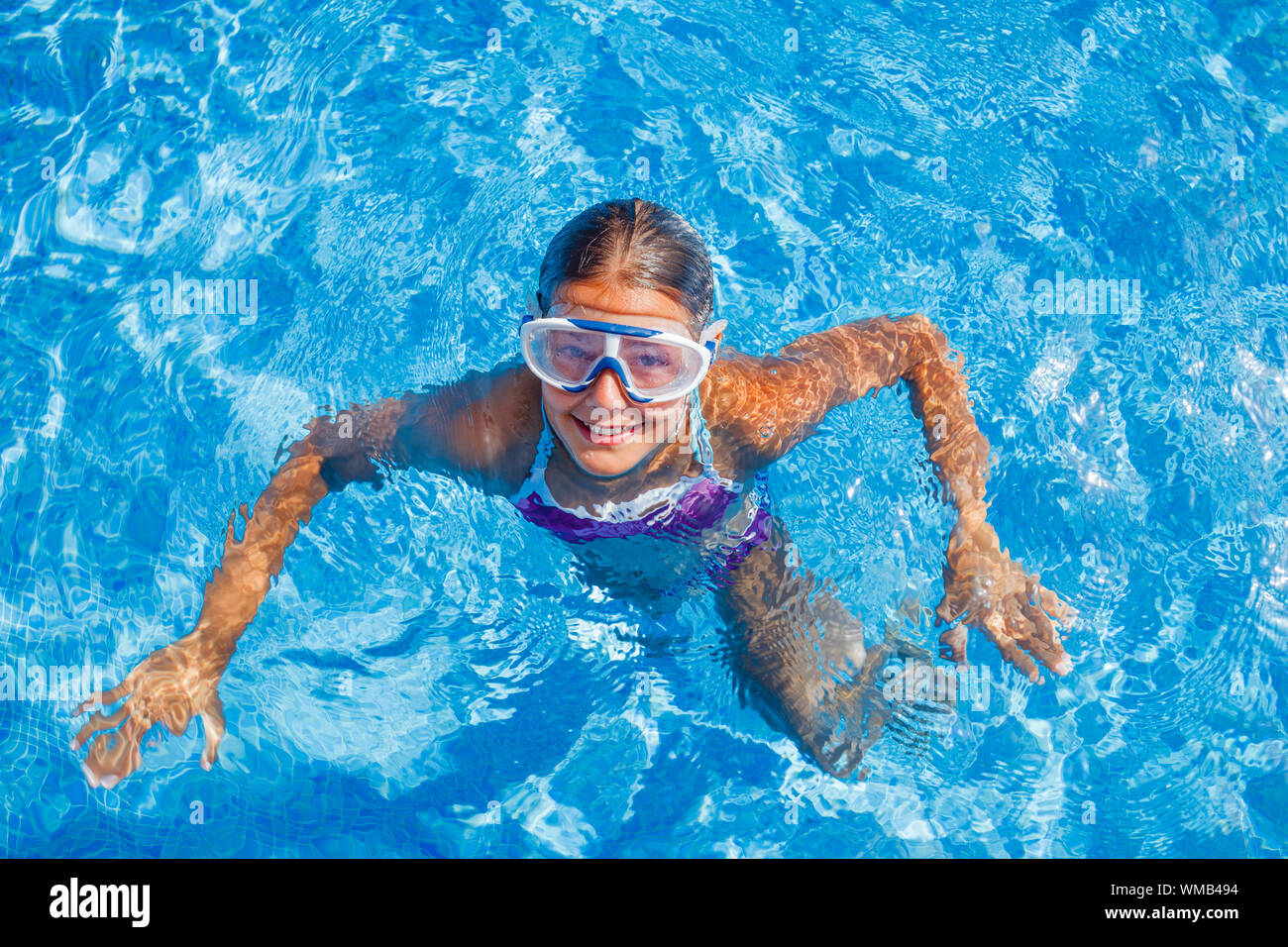 Carino felice giovane ragazza in occhiali nuoto e snorking in piscina Foto Stock