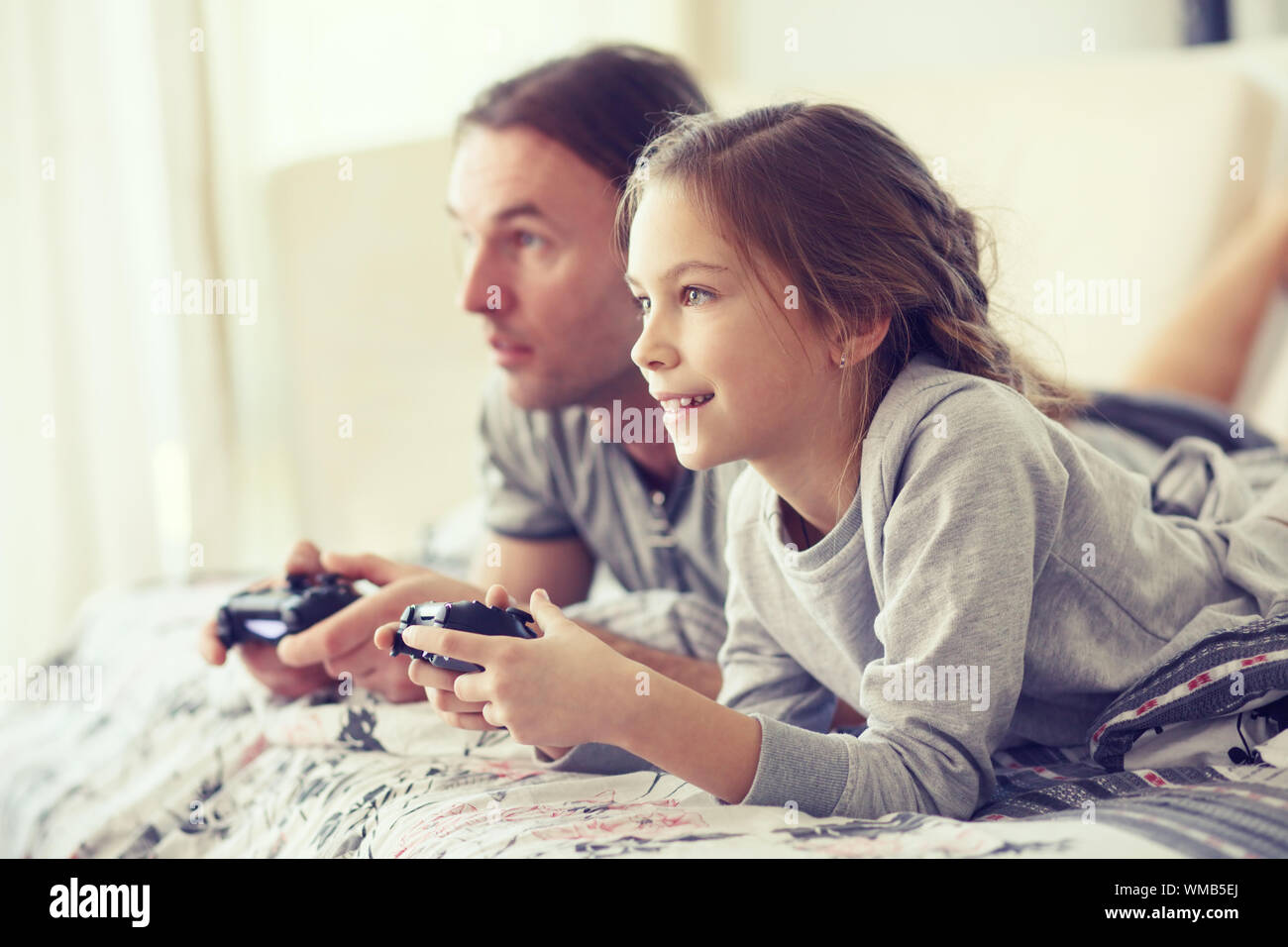 Bambino la riproduzione del video gioco su tv con padre in mattinata a letto di casa Foto Stock