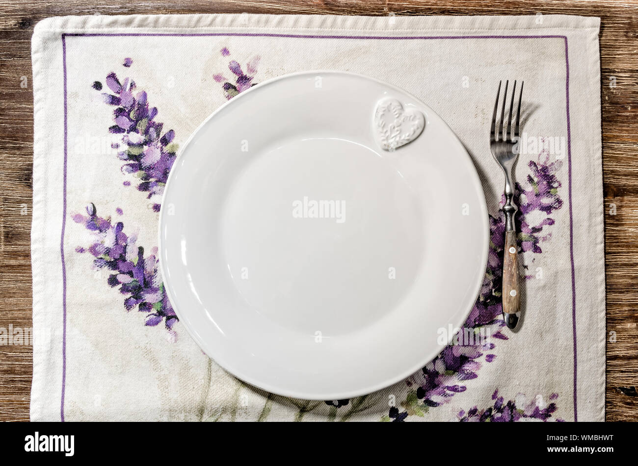 Piastra e forcella prevista su vintage tavolo da pranzo in legno con tovaglia colorata Foto Stock