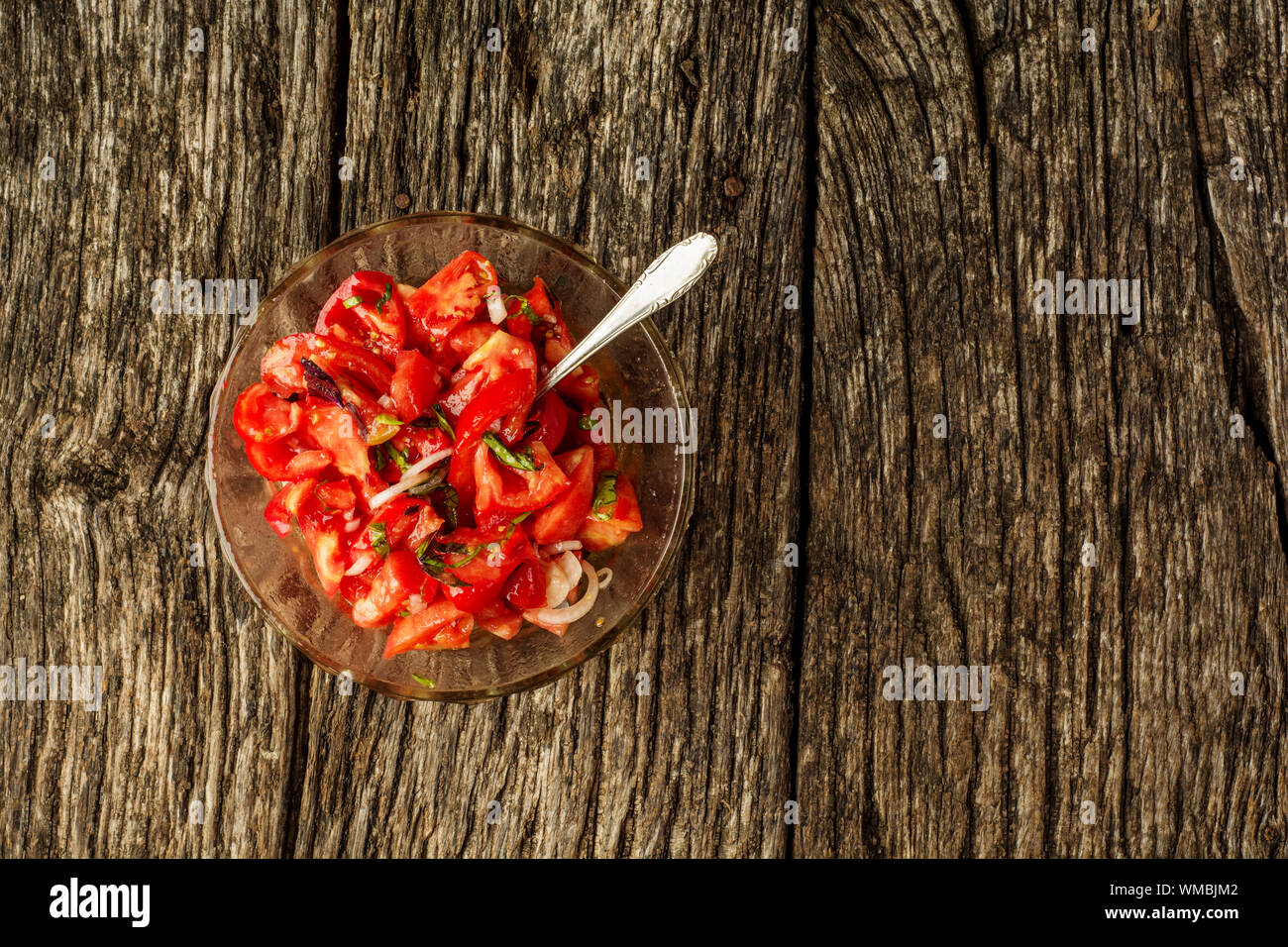 Insalata fresca e sana con pomodori, cipolle e basilico, piatto estivo fatto in casa. Sfondo piatto Foto Stock