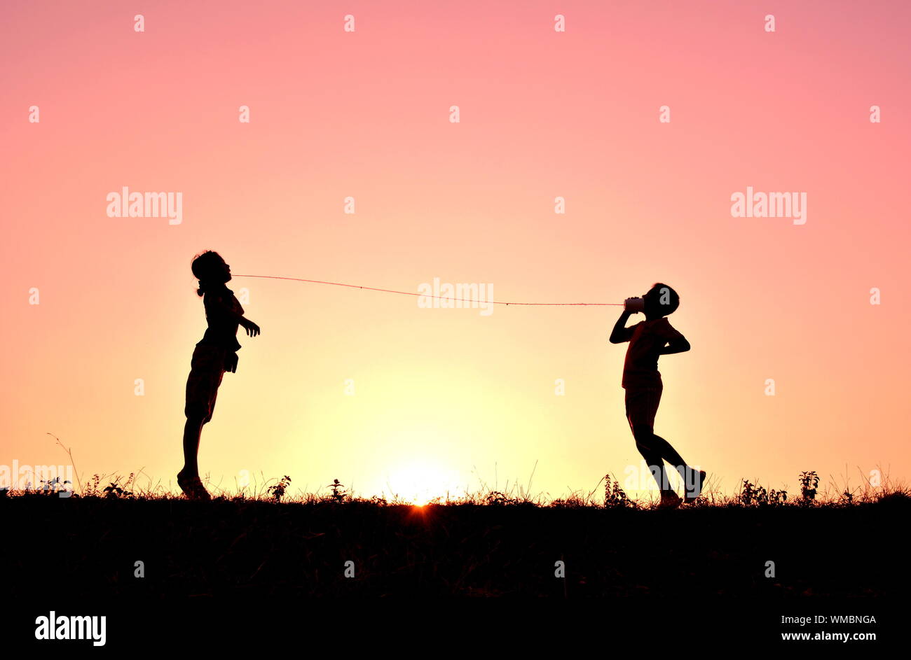 Silhouette di due persone che saltano contro il cielo al tramonto Foto Stock