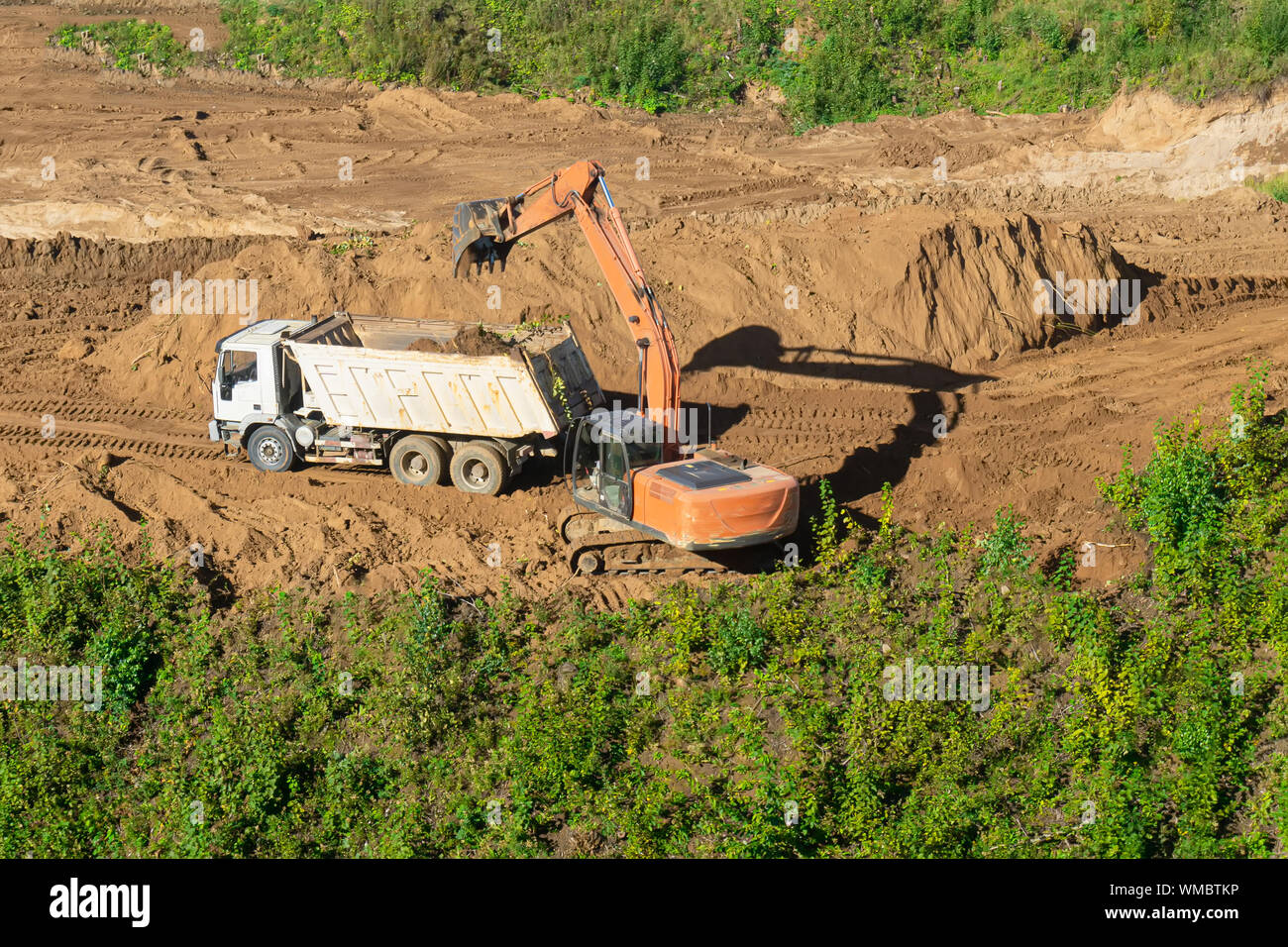 Caricamento escavatore dumper con sabbia al sito in costruzione. Foto Stock