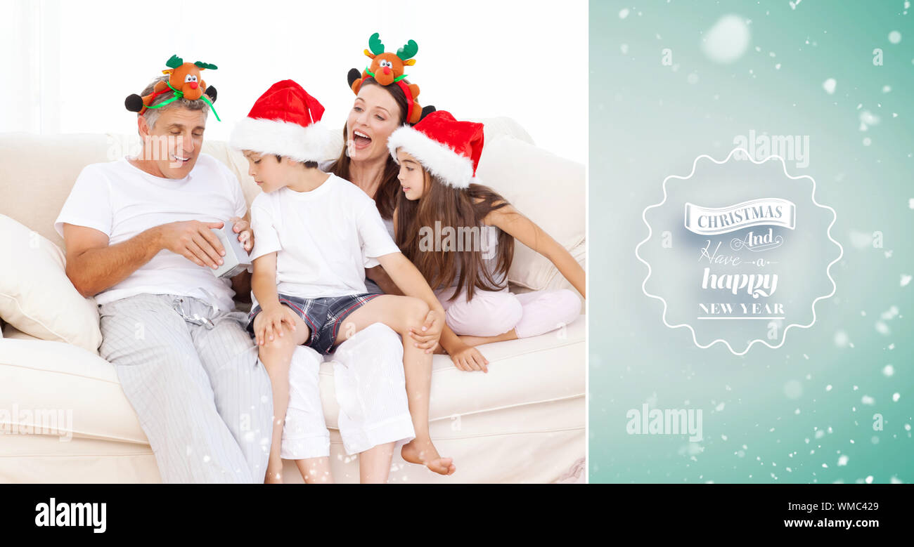 Famiglia il giorno di Natale guardando la loro presenta a casa contro il bollino verde Foto Stock