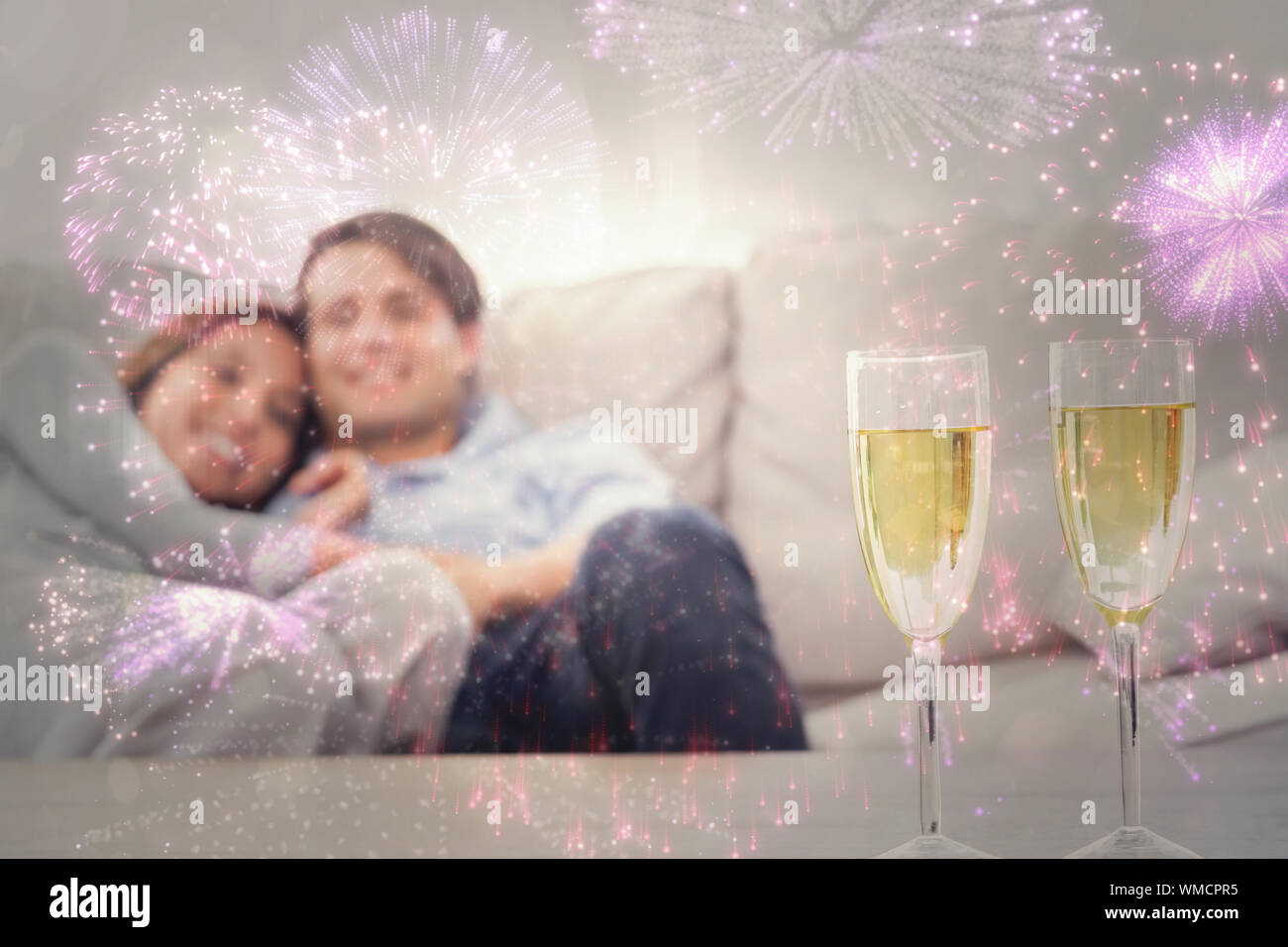 Matura in appoggio su di un lettino con flauti di champagne contro coloratissimi fuochi d'artificio impazza su sfondo nero Foto Stock