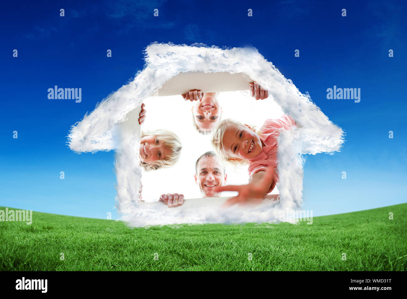La famiglia felice disimballaggio scatole contro campo verde sotto il cielo blu Foto Stock
