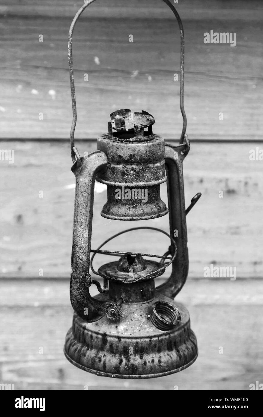 Vecchio arrugginito cherosene rosso lampada grigio sulla parete in legno sfondo. Bianco e nero, in stile retrò foto Foto Stock