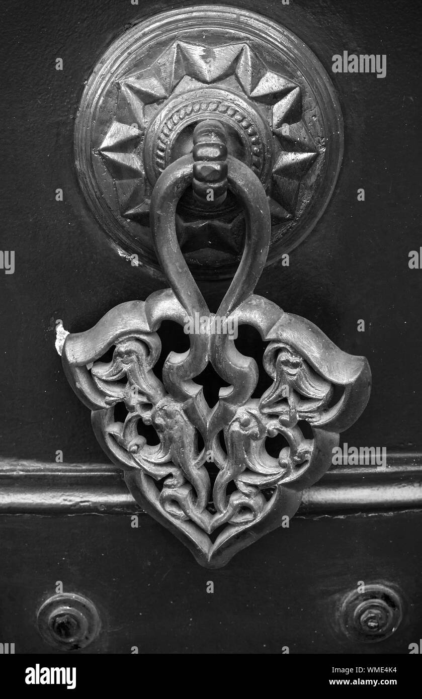 Rame antico manopola dello sportello con pattern arabo su nero cancello di legno. Izmir, Turchia. Bianco e nero, in stile retrò foto Foto Stock