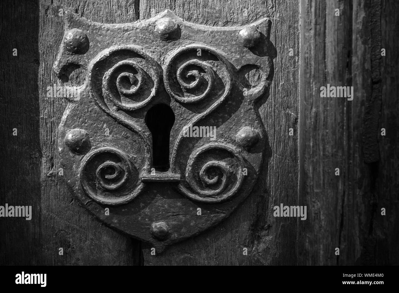 Metallo Vintage keyhole elemento decorativo su weathered superficie di legno. Bianco e nero, in stile retrò foto Foto Stock