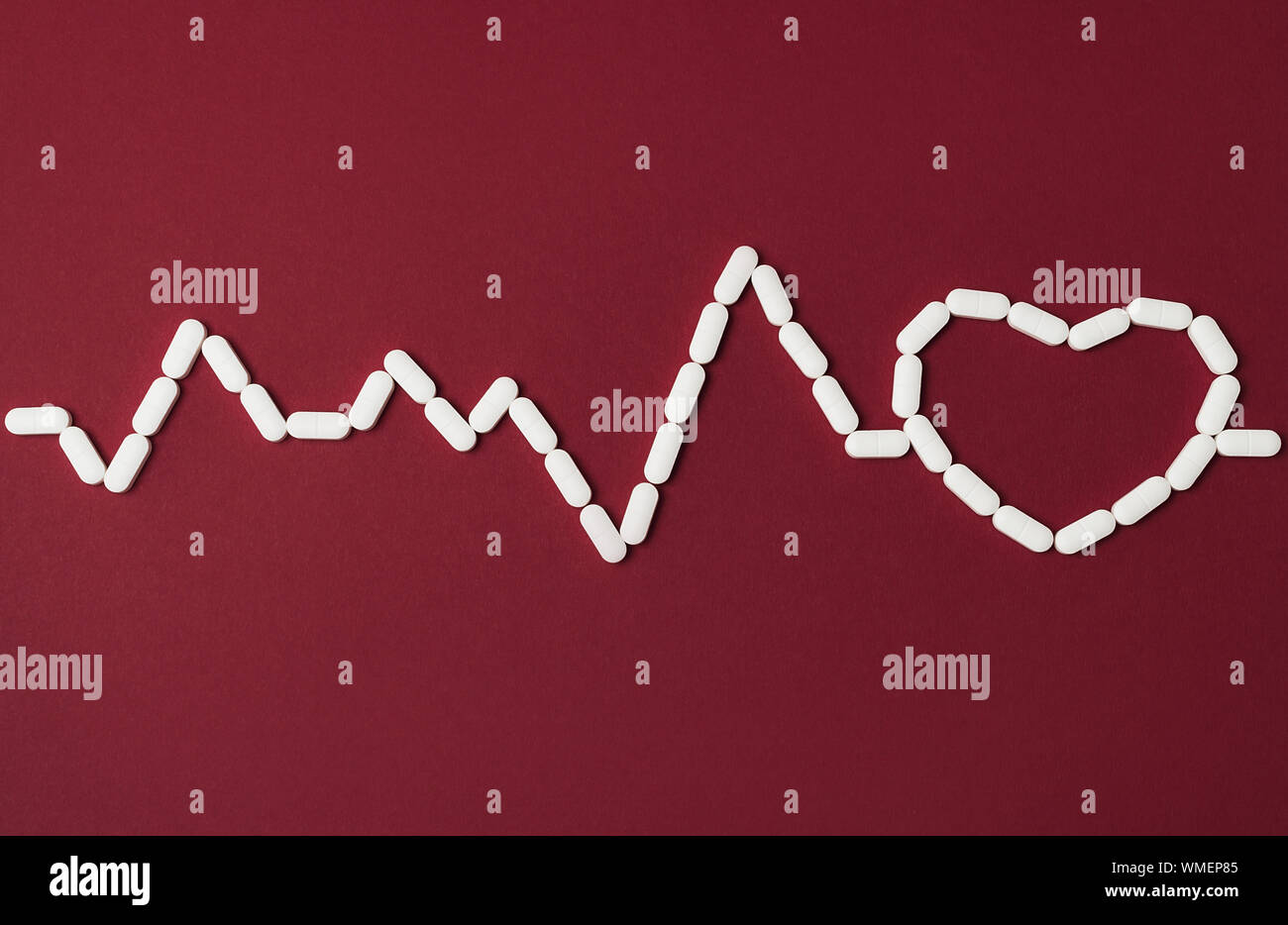 Pillole di bianco in una forma di heartbeat e cuore su sfondo rosso. Piatto stile di laici. Copia dello spazio. Medicina, sanità e farmacia concetto. Foto Stock